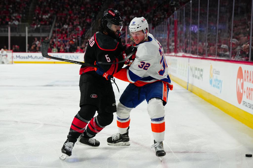 Carolina Hurricanes defenseman Jalen Chatfield (5) checks New York Islanders center Kyle MacLean (32) during the second period in game two of the first round of the 2024 Stanley Cup Playoffs at PNC Arena. 