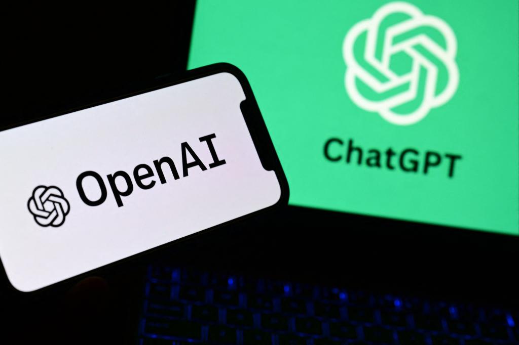 A hand holding a smartphone displaying the OpenAI and ChatGPT logos with a laptop in the background showing the same logos