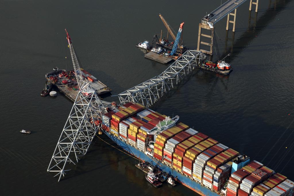 In an aerial view, salvage crews use a cranes to remove wreckage from the cargo ship Dali after it stuck and collapsed the Francis Scott Key Bridge.