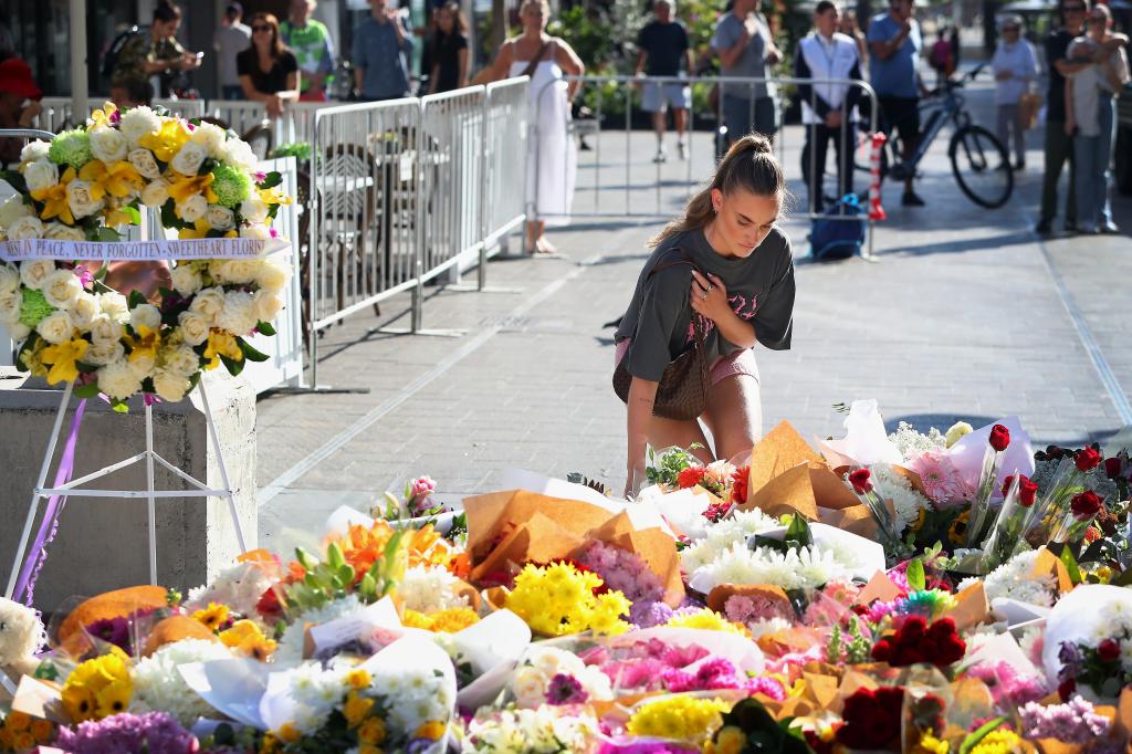 A woman leaving flowers at a memorial for the victims at Westfield Bondi Junction on April 14, 2024.