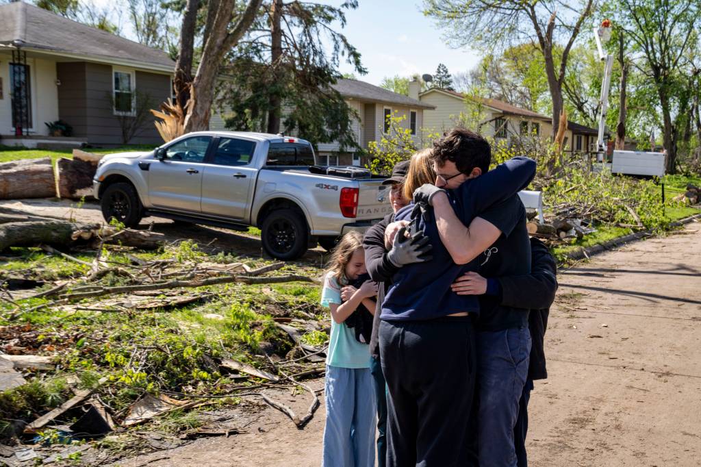 Neighbors comforting Penny Thomsen outside of her house in Pleasant Hill, Des Moines suburb, in the aftermath of tornado damage