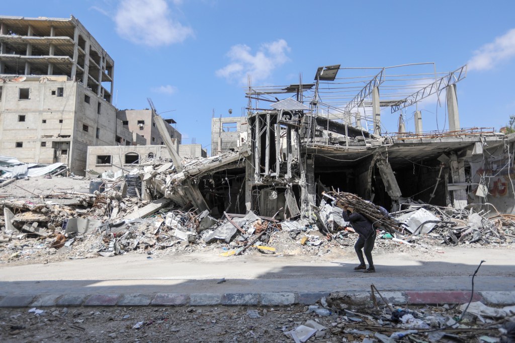 A man carries items on his back as people remove possessions from their homes following Israeli airstrikes on April 13, 2024 in Khan Yunis, Gaza