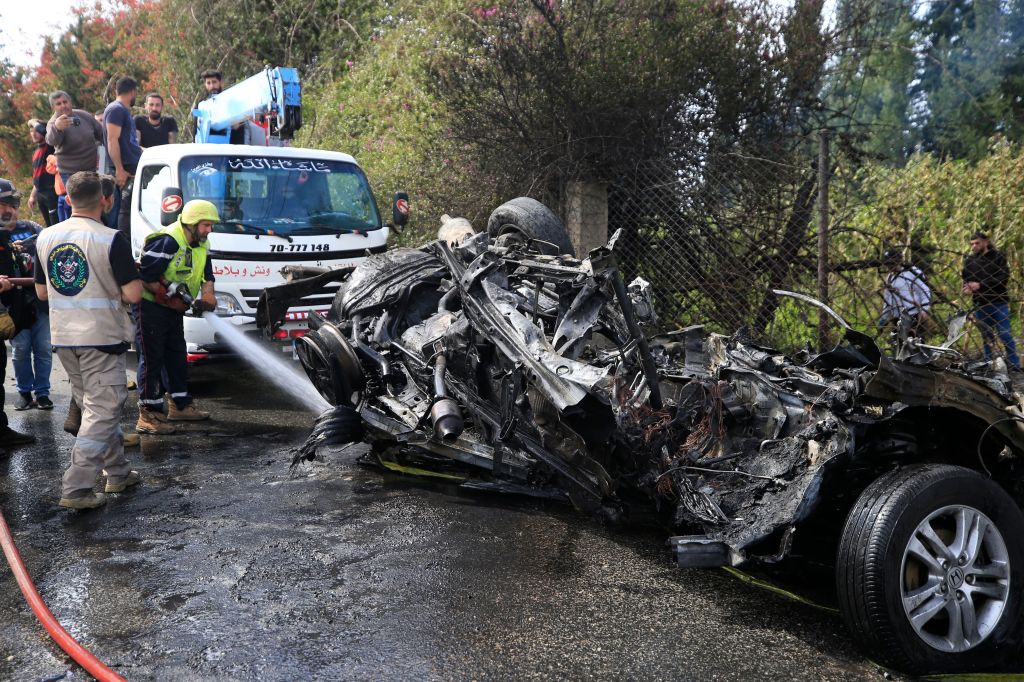 A firefighter douses a burning car targeted by an Israeli drone on Al Hoash Road, near the coastal city of Tyre, southern Lebanon, 13 March 