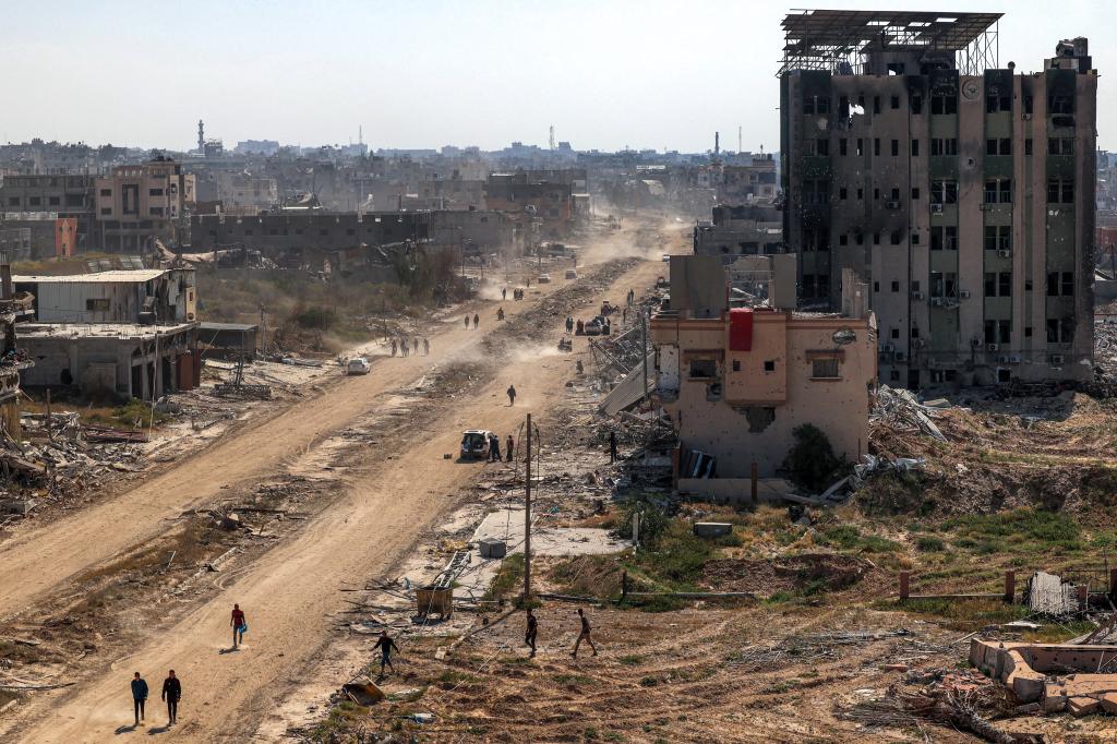 People walk near the ravaged building of al-Salam hospital (R) in Khan Yunis on April 7, 2024 after Israel pulled its ground forces out of the southern Gaza Strip.