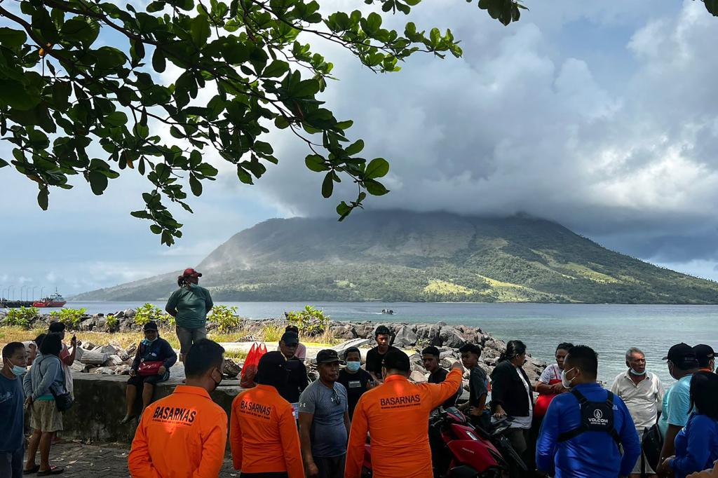 People in Sitaro, North Sulawesi look on toward the Mount Ruang volcano, as it spews smoke on April 18, 2024. 