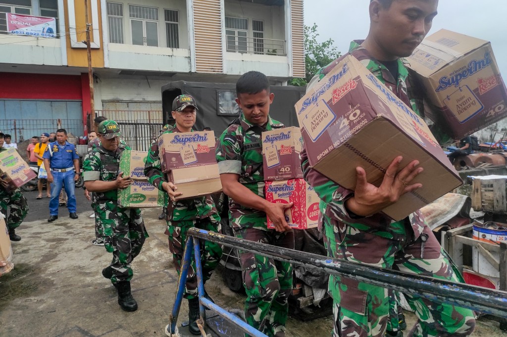 Indonesian military personnel load food items onto a ship as they head to the island near Mount Ruang volcano at the port in Manado, North Sulawesi, on April 18, 2024. 