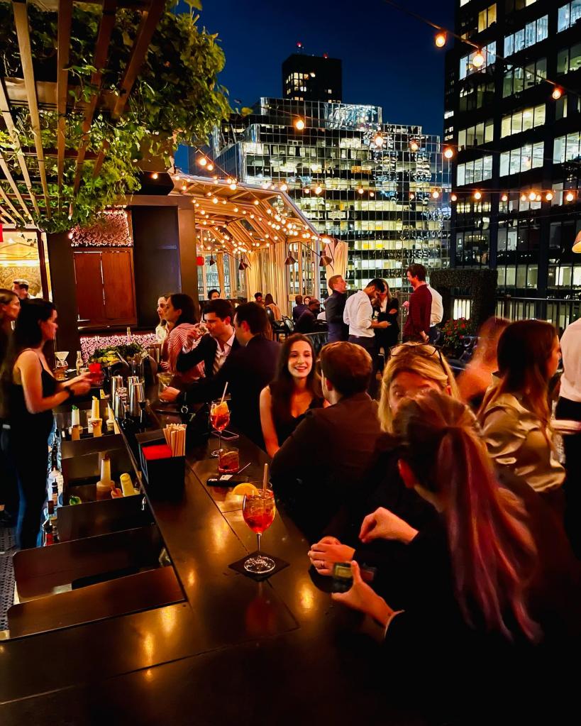 A group of people sitting at a rooftop bar in Upstairs at The Kimberly Hotel in Manhattan