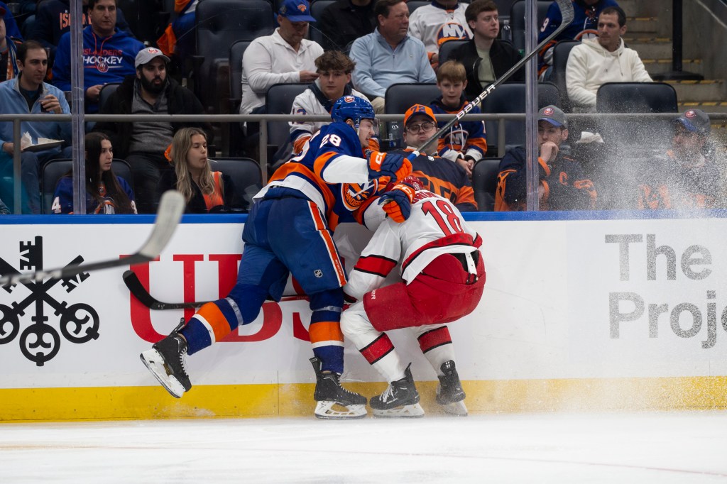 Alexander Romanov #28 of the New York Islanders checks Jack Drury #18 of the Carolina Hurricanes