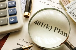 Magnifying glass, calculator, and pen on a document titled 401k plan on a table.