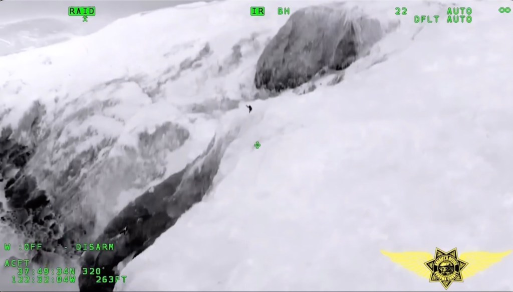 Thermal imagining camera shows the man on the side of the snowy cliff