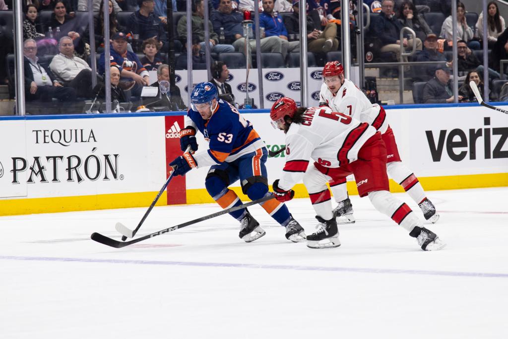 Casey Cizikas #53 of the New York Islanders and Jalen Chatfield #5 of the Carolina Hurricanes battle for puck
