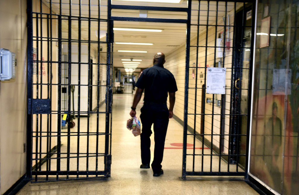 Rikers Island a guard walks through a gate into a hallway in rikers