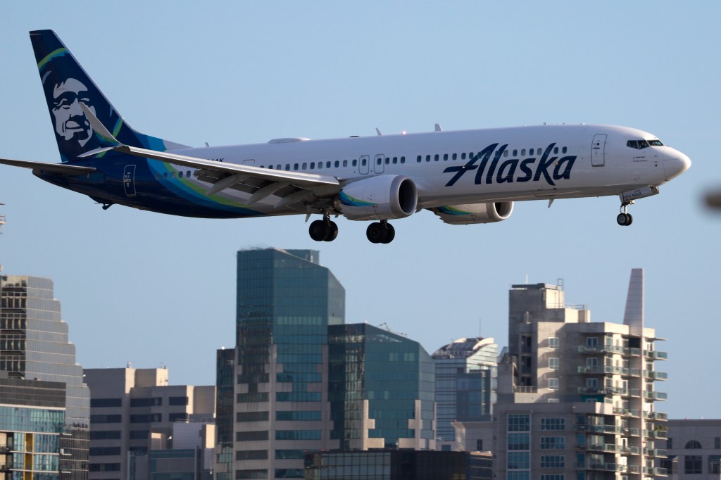 Alaska Airlines Boeing 737 MAX 9 aircraft approaching San Diego International Airport with residential and commercial buildings in the background