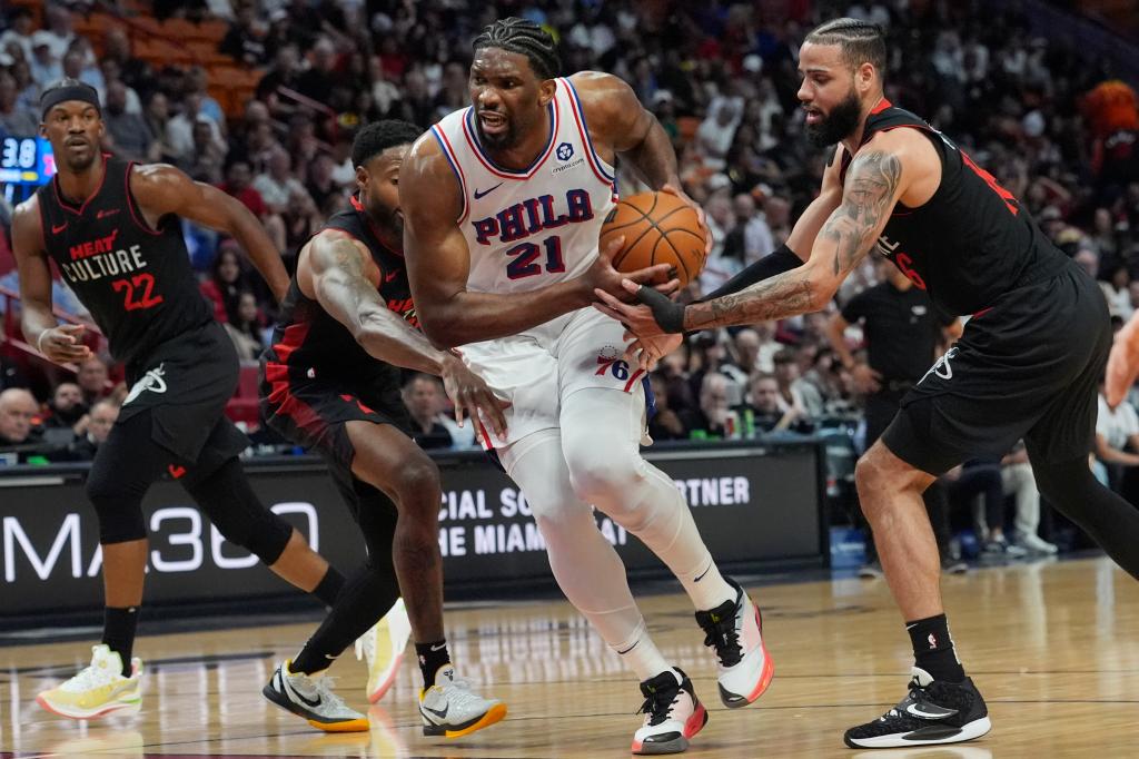 Philadelphia 76ers center Joel Embiid (21) breaks away from Miami Heat forward Haywood Highsmith and forward Caleb Martin during the first half of an NBA basketball game, Thursday, April 4, 2024, in Miami.