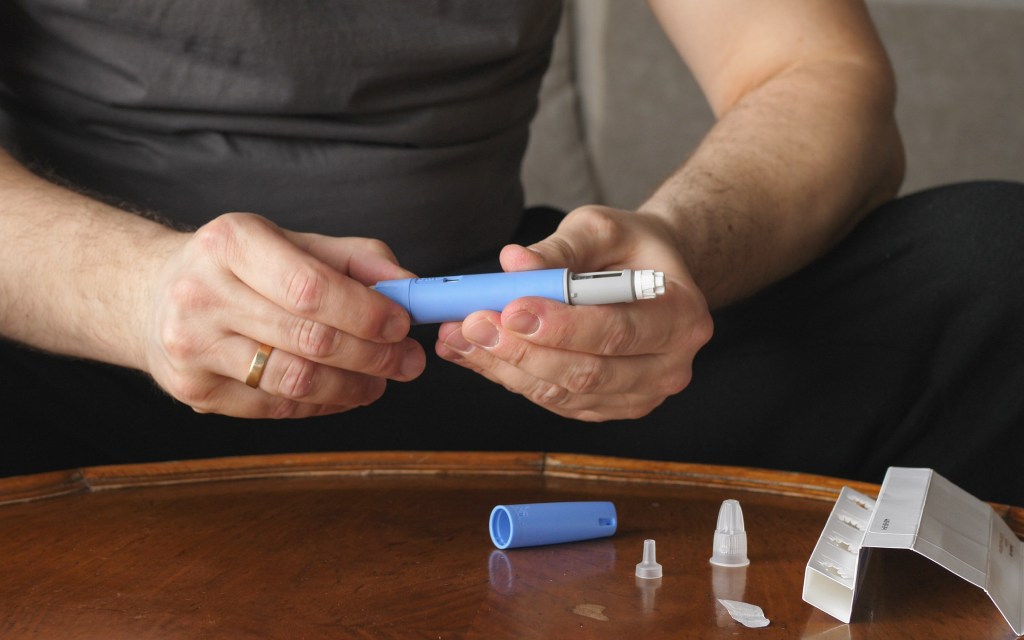 Overweight man preparing to administer Semaglutide Ozempic injection to control his blood sugar levels