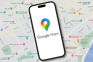 Google Maps logo with lettering is displayed on a smartphone lying on a map view of Google Maps