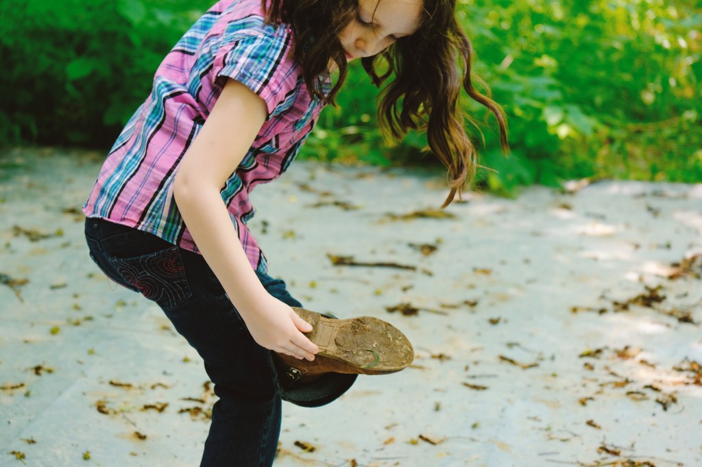 A woman examines a smear of dog poop on the bottom of her shoe.