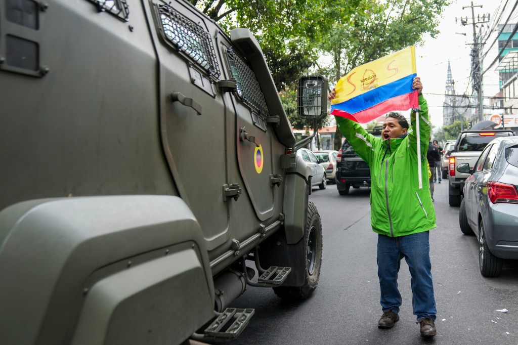 A man holding a flag next to a military vehicle