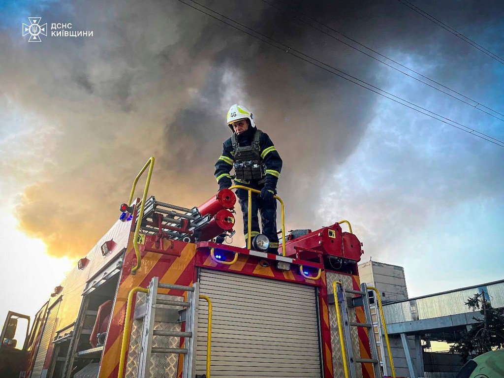 A firefighter stands on top of a fire truck during the massive blaze caused by Russia's attack on the Trypilska thermal power plant in Ukrainka, Ukraine, on April 11, 2024. 