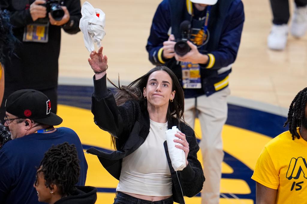 Caitlin Clark throws a tee-shirt to a fan during a time out between the Indiana Pacers and the Milwaukee Bucks.