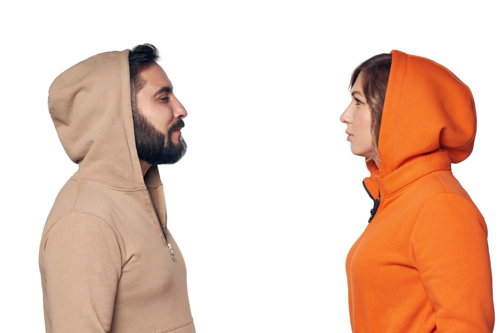 Young couple in casual clothes standing face to face looking at each other with intense