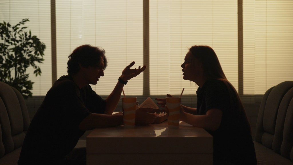 Silhouette of man and girl sitting at the bistro bar talking, arguing, angry face expression tense conversation.