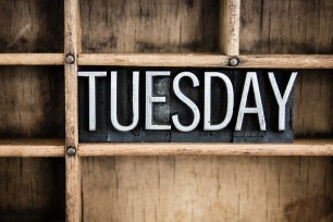 The word "TUESDAY" written in vintage metal letterpress type in a wooden drawer with dividers.