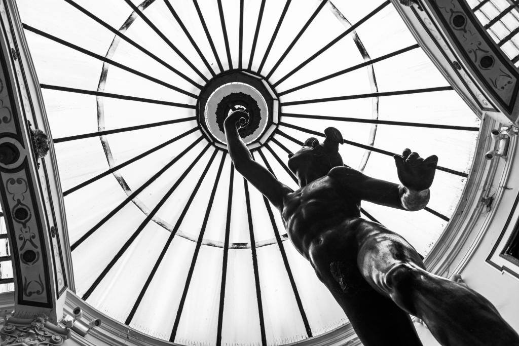 Black and white inside view of Pasaje Gutierrez in Valladolid, a shopping gallery designed by architect Jerome Ortiz de Urbina in 1885, with the lamp statue of Mercury (god of merchants) in its center under the glass dome. The statue is a replica of a Mercury by Jean Boulogne (1529-1608).