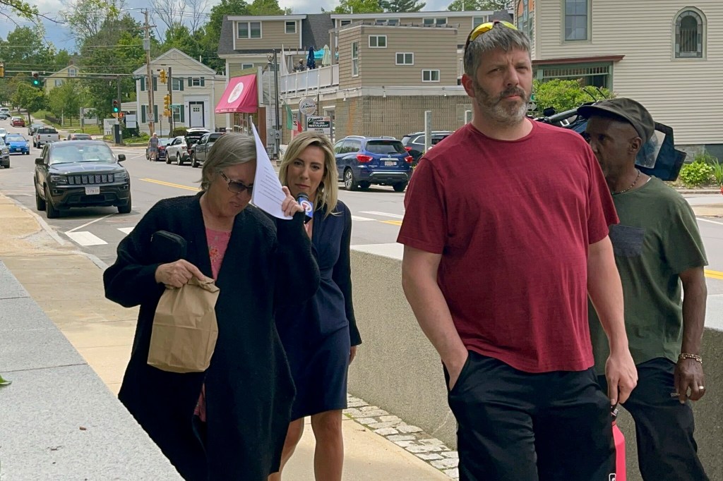 FILE - Denise Lodge, left, covers her face with a printout of the indictment against her as she walks from the federal courthouse.