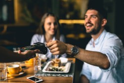 A couple eats dinner at a restaurant and pays with a credit card.