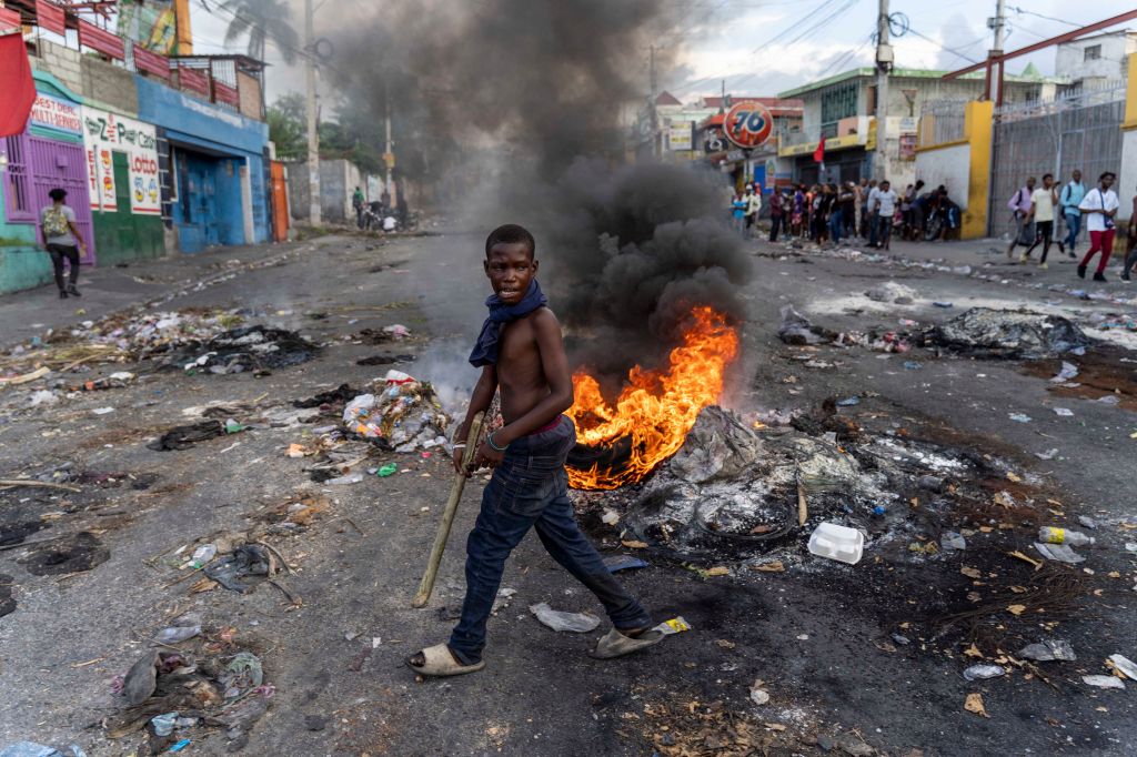 A mans walks past a burning barricade during a protest against Haitian Prime Minister Ariel Henry calling for his resignation, in Port-au-Prince, Haiti,