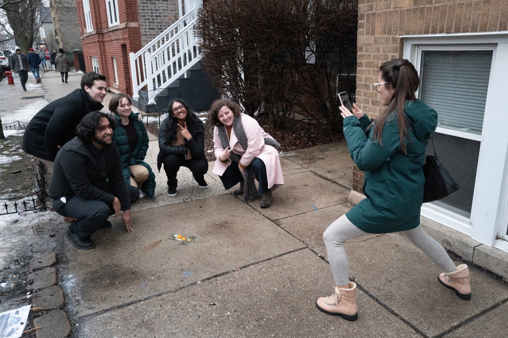 People pose for a picture in front of an impression in a sidewalk in the Roscoe Village neighborhood known as the Chicago Rat Hole on January 24, 2024 in Chicago, Illinois.