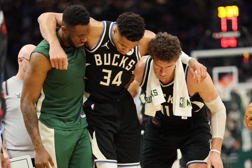 Giannis Antetokounmpo is helped off the court by Thanasis Antetokounmpo and Brook Lopez after suffering an injury during the second half of a game against the Boston Celtics at Fiserv Forum on April 09, 2024.