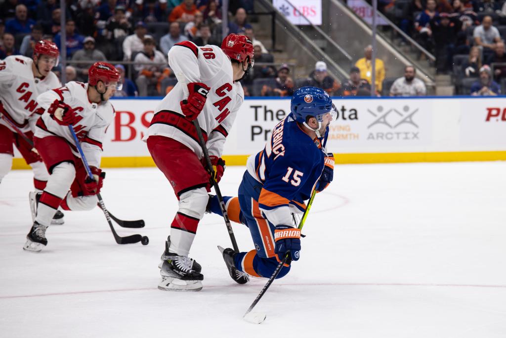 Teuvo Teravainen #86 of the Carolina Hurricanes trips Cal Clutterbuck #15 of the New York Islanders i