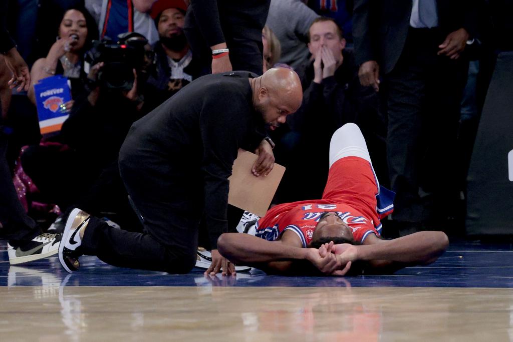 Joel Embiid lies on the floor after injuring his left knee again on a dunk during the second quarter of the Knicks' 111-104 win over the 76ers.