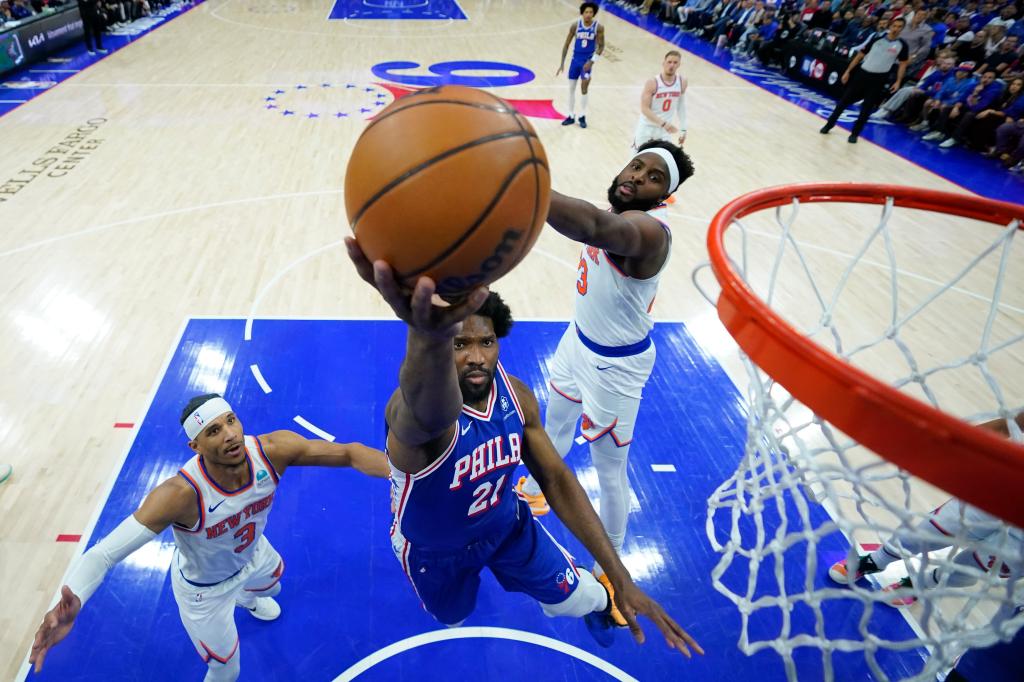 Joel Embiid goes up for a layup after driving past Mitchell Robinson (right) and Josh Hart during the Knicks' loss to the 76ers.