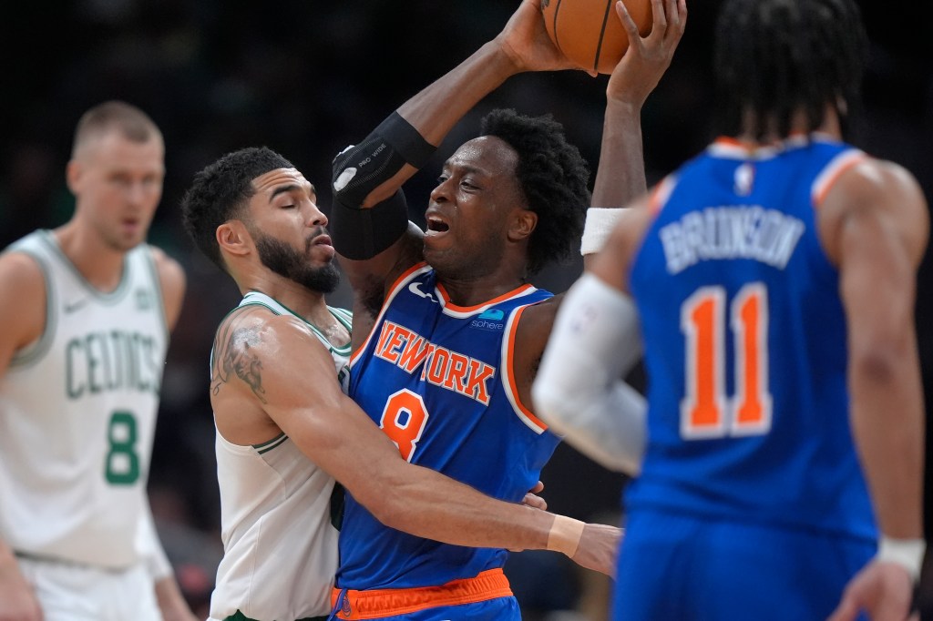 New York Knicks forward OG Anunoby, center right, looks to pass the ball as Boston Celtics forward Jayson Tatum, center left, defends in the first half of an NBA basketball game, Thursday, April 11, 2024, in Boston.
