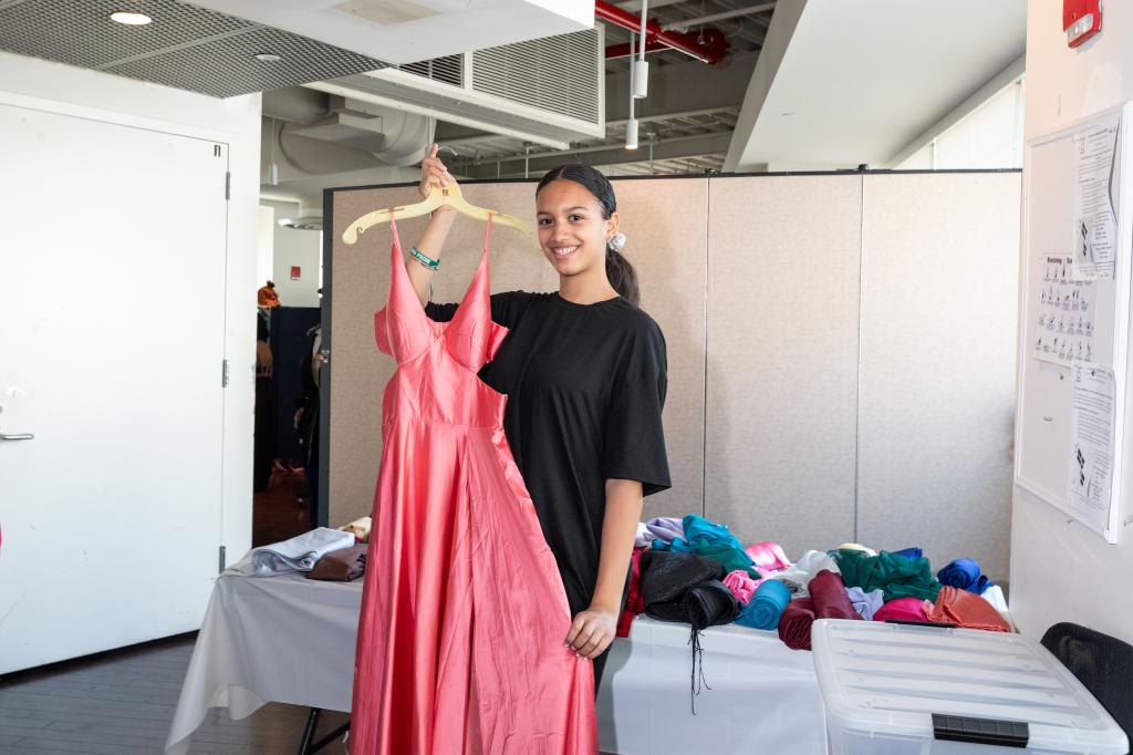 Alyssa, 14, holding a pink dress she picked out at the prom clothing giveaway event