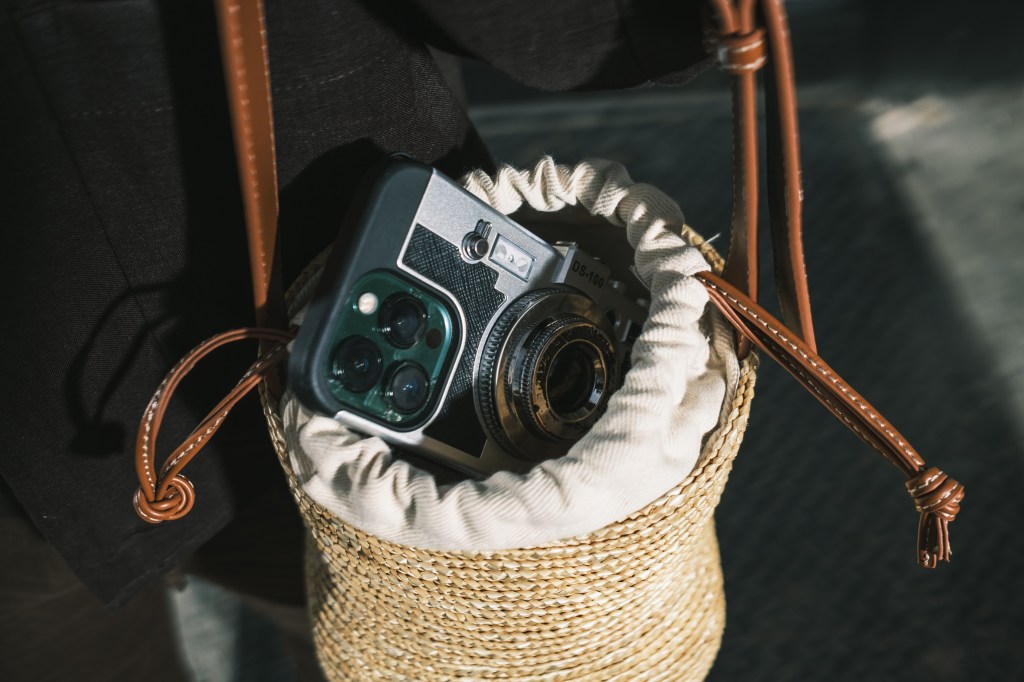 CJ Robinson, an art director, placing his phone with a camera case inside a Zara Basket Bag outside Little Caribbean in Brooklyn, New York