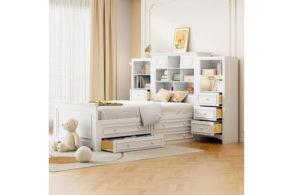 A white bed with a white bookcase and a teddy bear