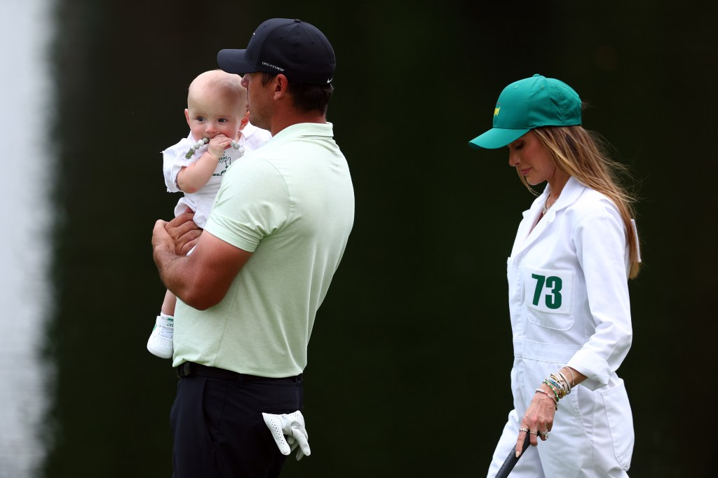 Brooks Koepka of the United States walks the fairway with wife, Jena Sims, son, Crew, during the Par Three Contest 