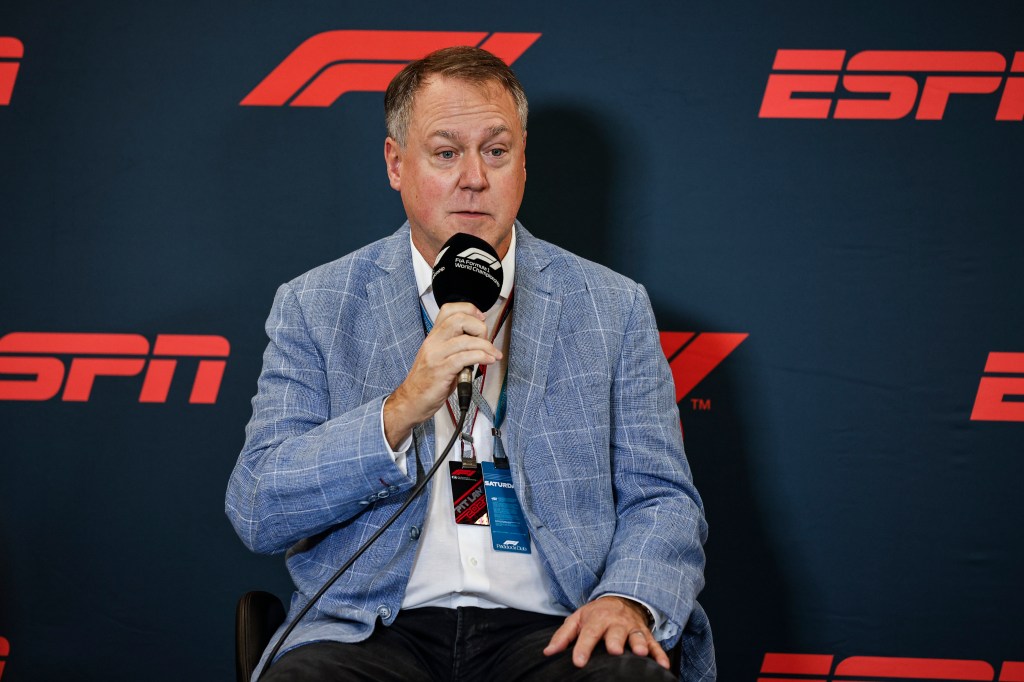 Burke Magnus, ESPN president, sitting in a chair holding a microphone at the F1 Grand Prix in Austin, Texas