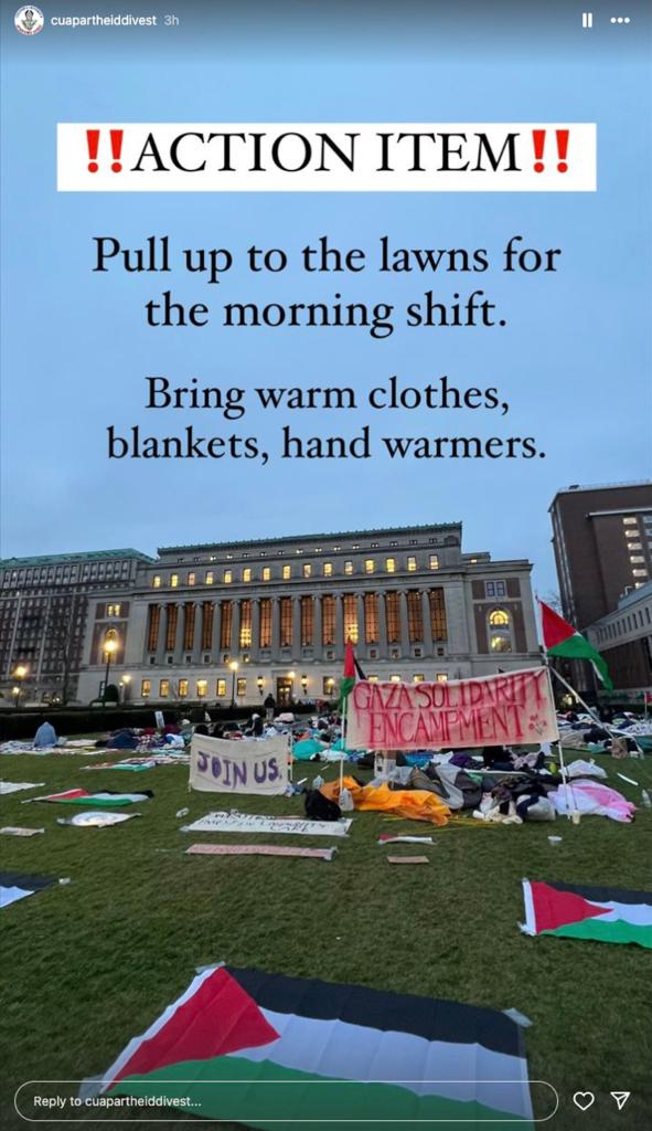 Columbia students reassembling their tent protest in front of a large university building cluttered with signs and posters