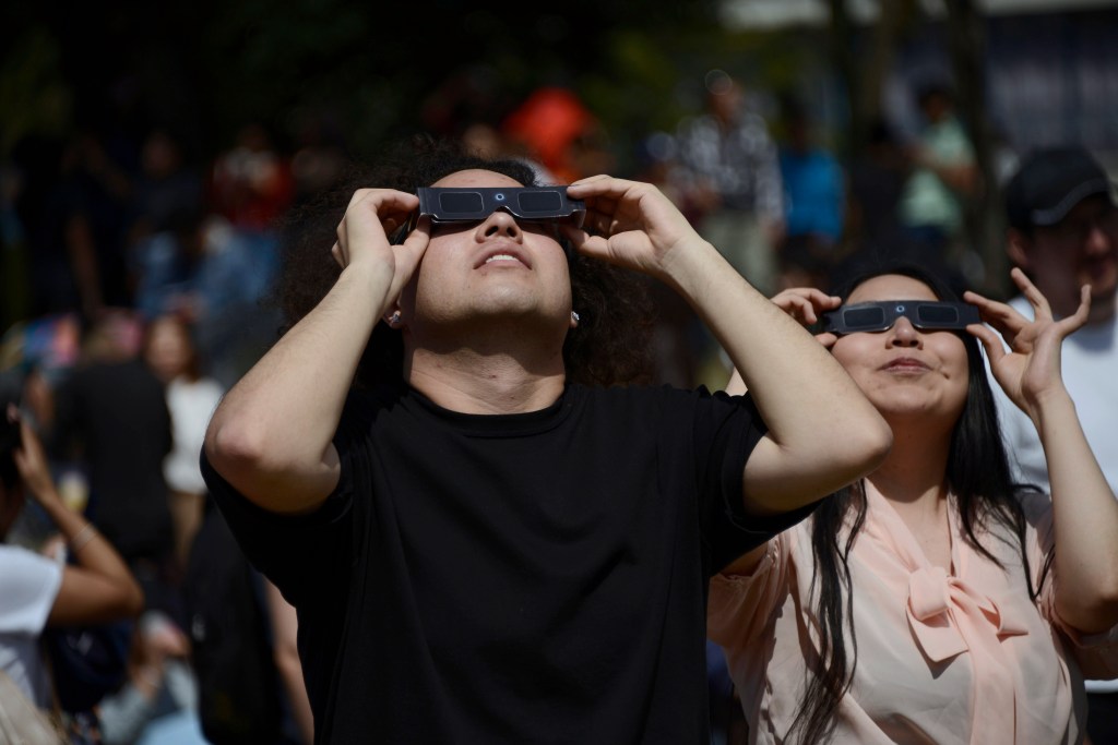 A couple is seen observing the annular solar eclipse with special filter glasses for the sun at the National Autonomous University of Mexico 
