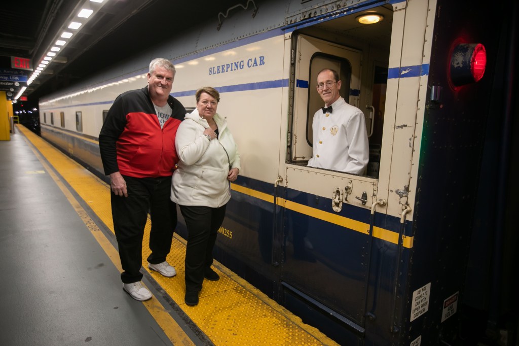 A photo of Don and Lisa Combs standing outside the vintage train.