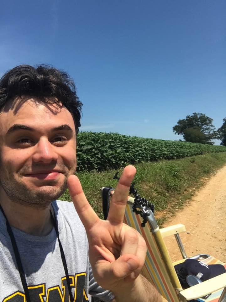 Dan Mescon flashes a Victory sign while standing alongside the soy bean field from which he watched the 2017 eclipse