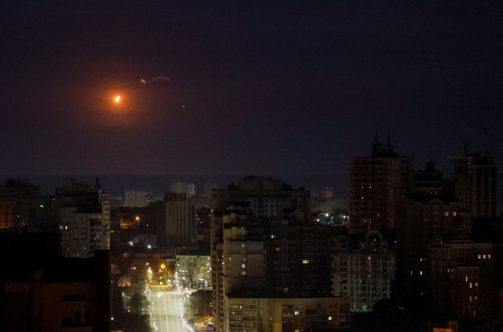 An explosion of a drone is seen in the sky over the city during a Russian missile strike.