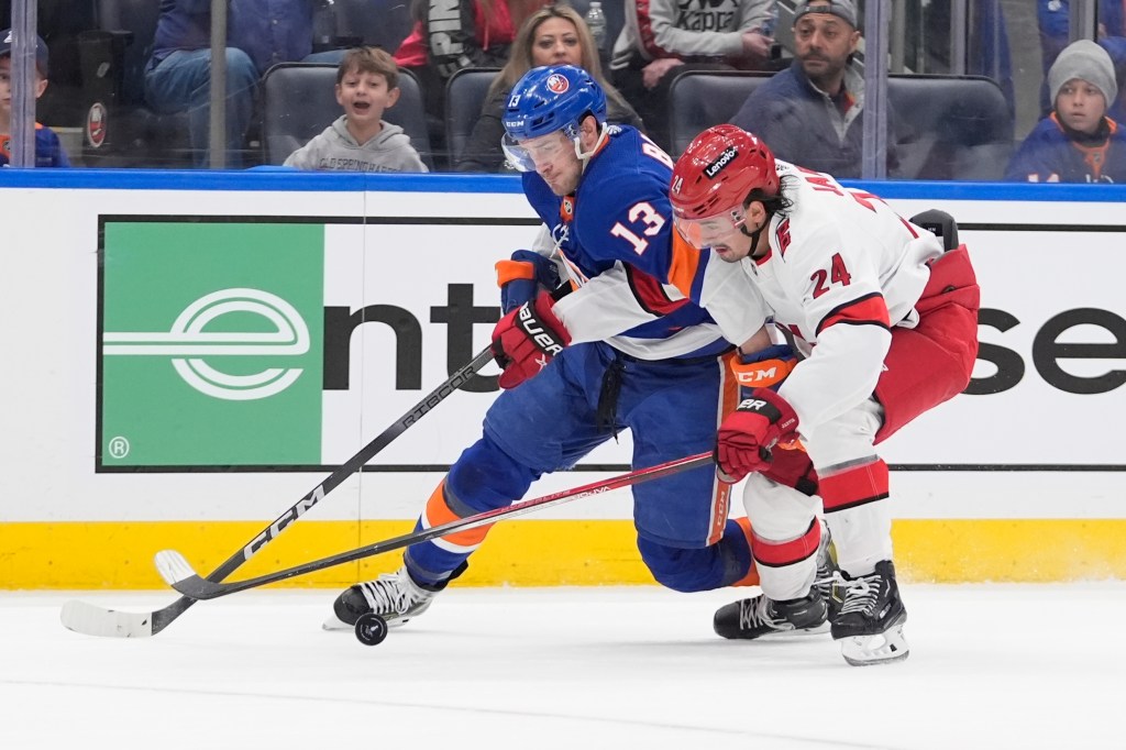 Hurricanes' Seth Jarvis (24) fights for control of the puck with New York Islanders' Mathew Barzal.