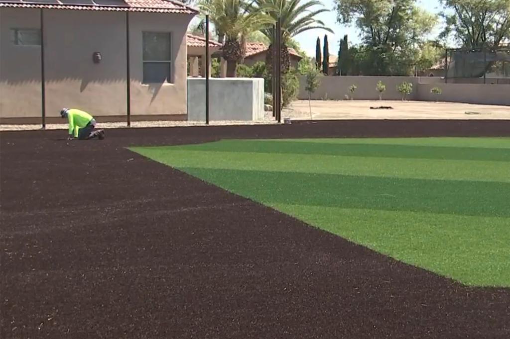 A worker installs turf for Hardy's new backyard field. 
