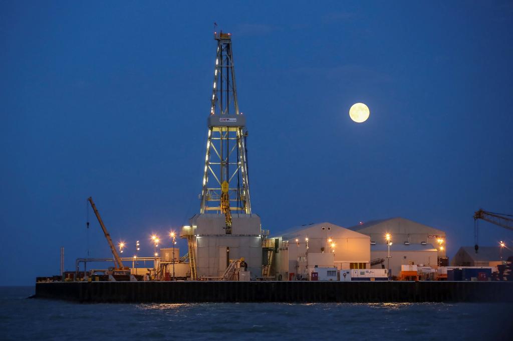 The full moon rises in the background over an oil rig at the Kashagan offshore oil field in the Caspian sea on August 21, 2013.